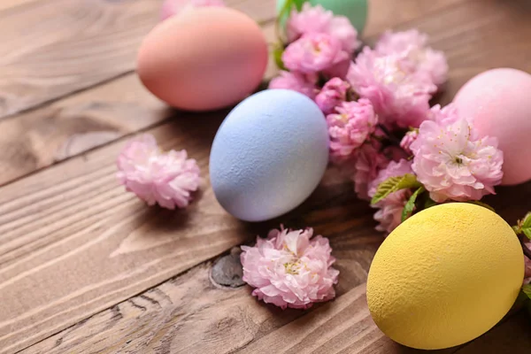 Beautiful Easter eggs with flowers on wooden background — Stock Photo, Image