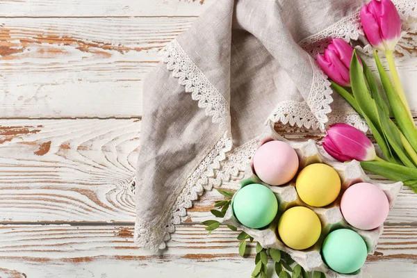 흰색 나무 테이블에 아름다운 부활절 달걀과 꽃 패키지 — 스톡 사진
