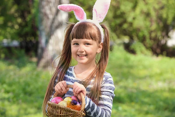 Menina com ovos de Páscoa e orelhas de coelho no parque — Fotografia de Stock