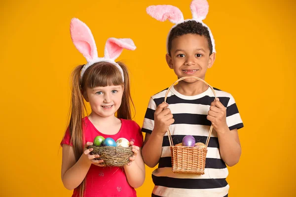 Małe dzieci z pisanki i uszy króliczka na kolorowym tle — Zdjęcie stockowe