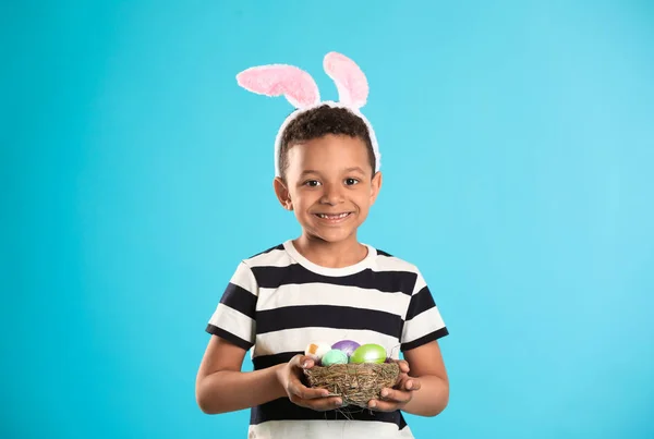 Renk arka planda Paskalya yumurtaları ve tavşan kulakları ile Küçük Afrikalı-Amerikalı çocuk — Stok fotoğraf