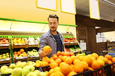 Genç adam süpermarkette yiyecek seçiyor.