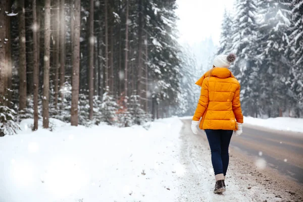 Beautiful young woman near road in winter forest — Stock Photo, Image