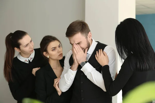 Familiares calmando joven viudo en funeral —  Fotos de Stock