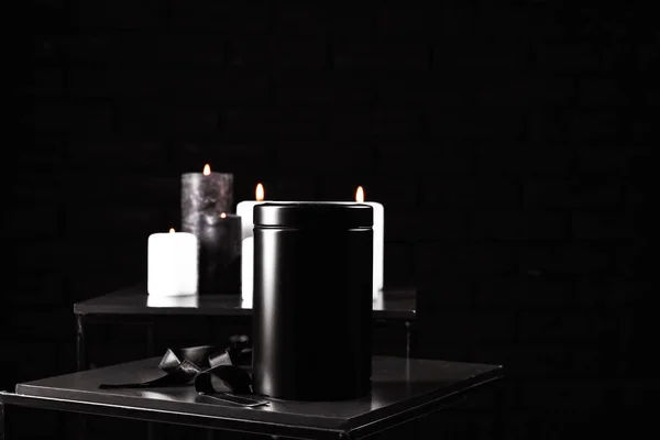 Моргуарна урна зі стрічкою на столі на темному фоні — стокове фото