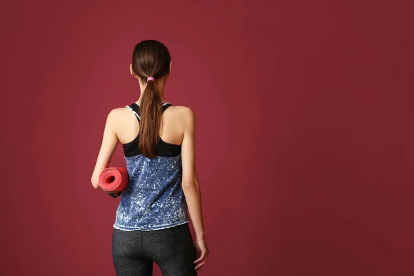 年轻的运动女人与瑜伽垫的颜色背景 — 图库照片