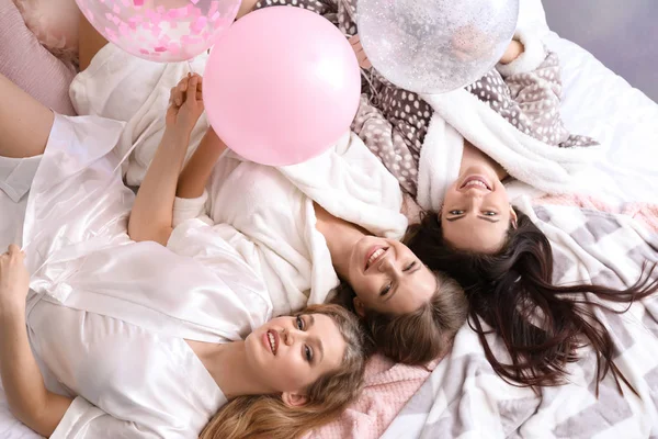 Beautiful young women lying on bed at hen party — Stock Photo, Image