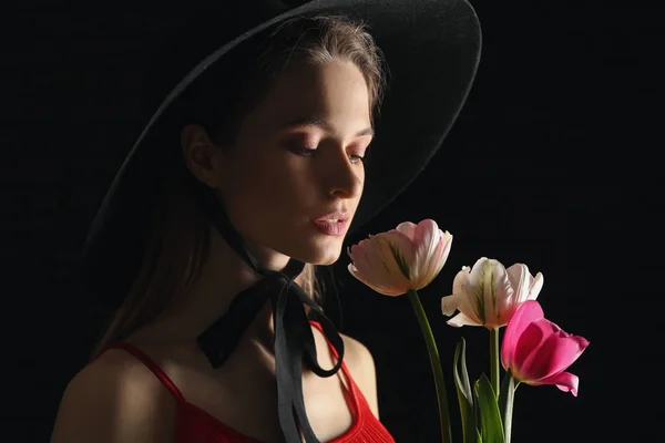 Young woman with bouquet of beautiful tulips on dark background — Stock Photo, Image