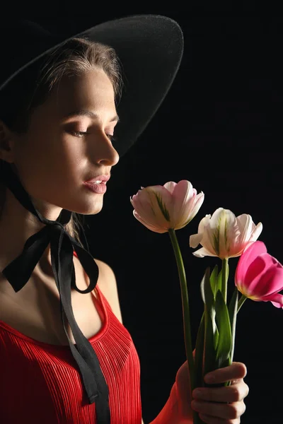 Young woman with bouquet of beautiful tulips on dark background — Stock Photo, Image