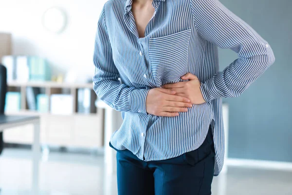 Giovane donna che soffre di mal di stomaco in ufficio — Foto Stock
