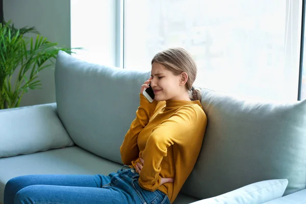 Une jeune femme appelle une ambulance alors qu'elle souffre de douleurs abdominales à la maison — Photo