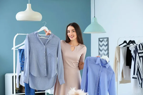 Jonge vrouw kiezen kleren in kleedkamer — Stockfoto