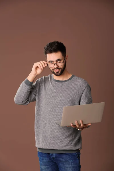 Male programmer with laptop on color background — Stock Photo, Image