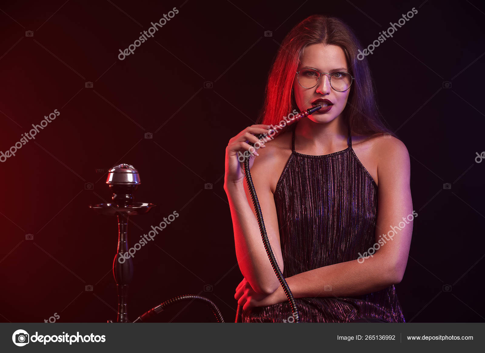 Joven mujer fumando narguile sobre fondo oscuro fotografía de stock