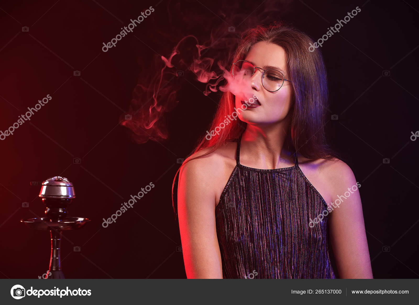 Joven mujer fumando narguile sobre fondo oscuro fotografía de stock