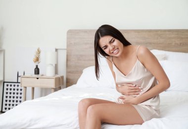 Genç kadın yatak odasında karın ağrısı muzdarip