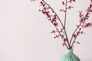 Işık arka planında çiçek açan güzel dalları olan vazo.