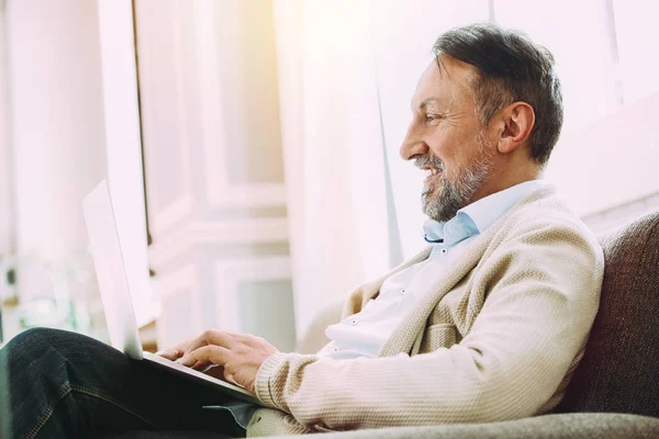Knappe volwassen man met laptop thuis — Stockfoto