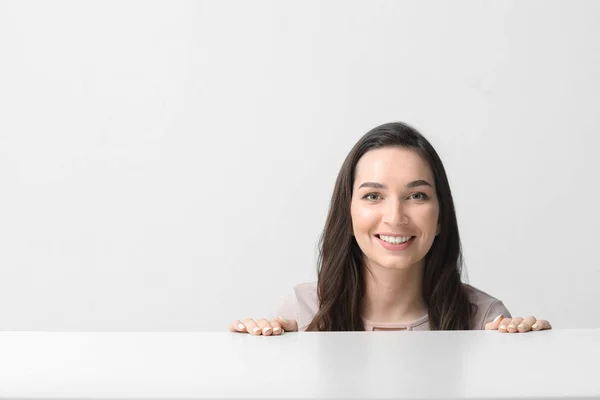 Beautiful young woman near table on white background — Stock Photo, Image