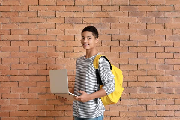 Afro-americano ragazzo adolescente con computer portatile vicino muro di mattoni — Foto Stock