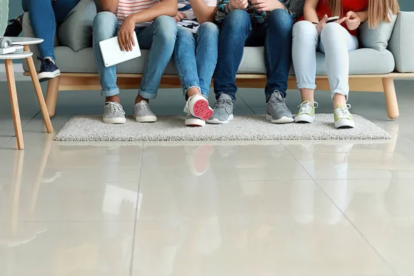 Group of teenagers sitting on sofa indoors