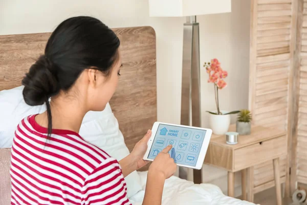 Young Asian woman using application of smart home automation in bedroom — Stock Photo, Image