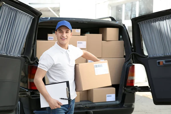 Handsome delivery man near car with parcels outdoors — Stock Photo, Image