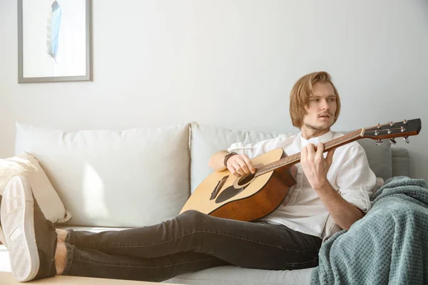 Joven guapo tocando la guitarra en casa — Foto de Stock