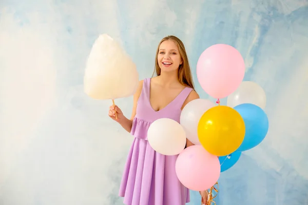 Красивая женщина с сахарной ватой и воздушными шарами на светлом фоне — стоковое фото