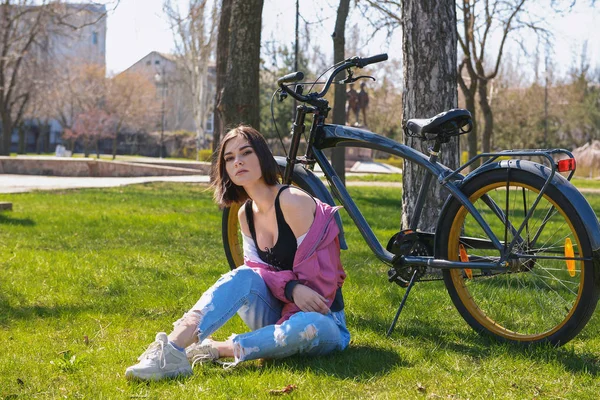 Hermosa joven con bicicleta en el parque en el día de primavera — Foto de Stock