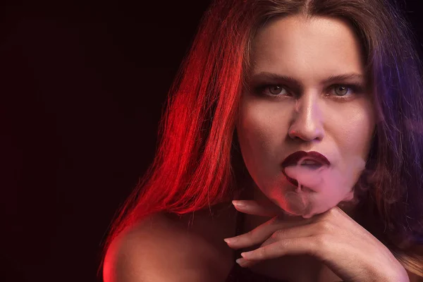 Young woman smoking on dark background — Stock Photo, Image