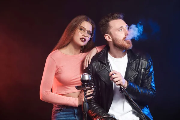 Young couple smoking hookah on dark background — Stock Photo, Image