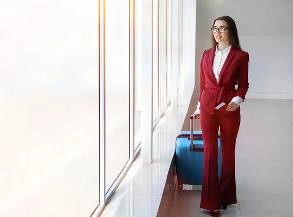 Идет молодая деловая женщина с чемоданом в зале аэропорта — стоковое фото