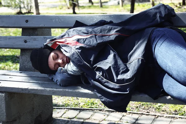 Poor homeless woman lying on bench outdoors Royalty Free Stock Photos