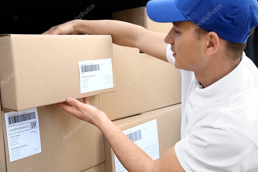 Delivery man taking parcel from car outdoors