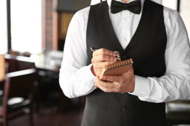 Restoranda defteri olan genç bir garson, yakın plan.
