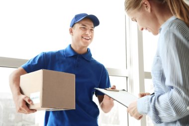 Woman signing documents to confirm receiving of order from delivery company
