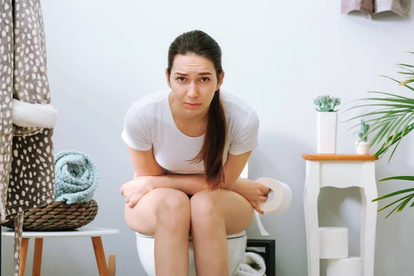 Young woman suffering from constipation on toilet bowl at home — Stock Photo, Image