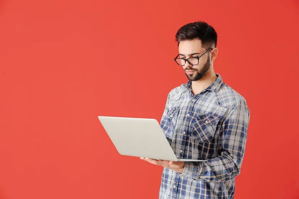 Male programmer with laptop on color background — Stock Photo, Image