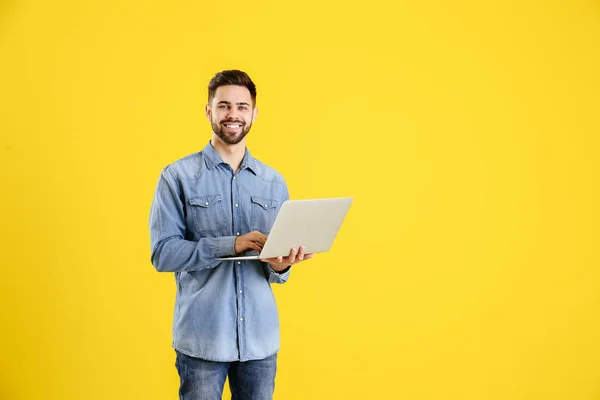 Male programmer with laptop on color background — Stock Photo, Image