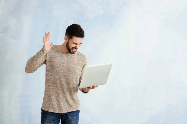 Angry male programmer with laptop on color background — Stock Photo, Image