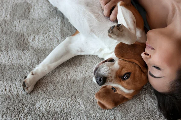 Young woman with cute dog lying on floor at home — Stock Photo, Image