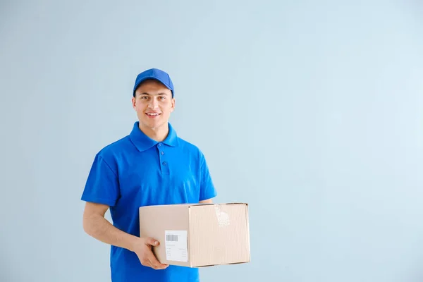 Delivery man with box on color background