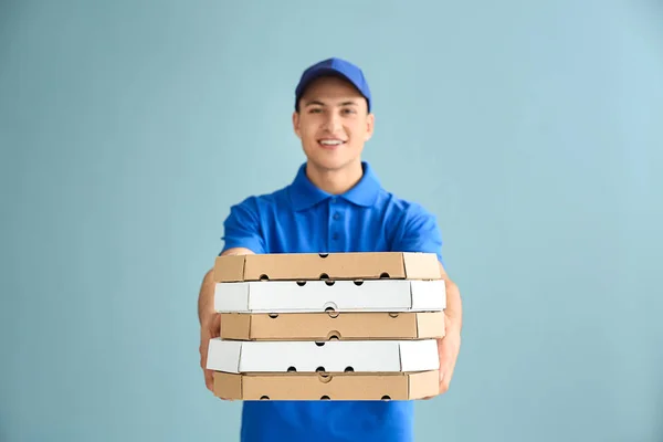 Delivery man with pizza boxes on color background