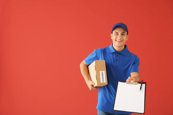 Entrega hombre con caja y portapapeles sobre fondo de color — Foto de Stock