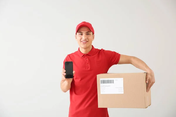 Doručovací muž s krabička a mobilním telefonem na pozadí — Stock fotografie