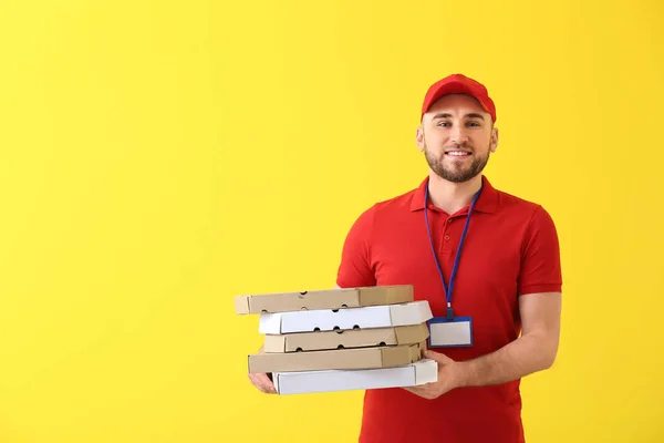 Handsome delivery man with pizza boxes on color background — Stock Photo, Image