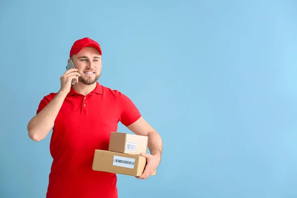 Przystojny człowiek dostawy z pudełka rozmowy przez telefon na tle kolorów — Zdjęcie stockowe