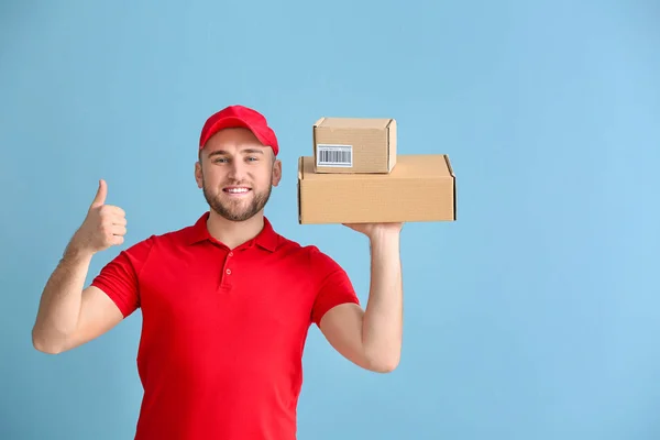 Pohledný muž s krabic s palcem nahoře na barevném pozadí — Stock fotografie
