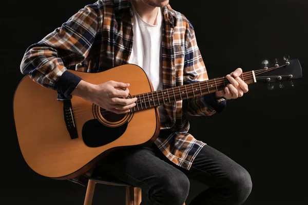 Handsome young man playing guitar on dark background — Stock Photo, Image